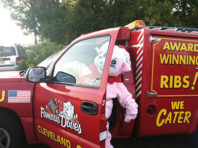 Famous Dave's pig mascot coming out of Famous Dave's bright red Catering Truck