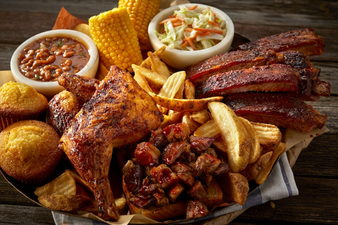 Famous Dave's Tuesday BBQ Feast piled high with chicken, ribs, fries, cornbread, corn, baked beans, and coleslaw