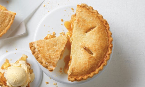 An Apple Pie topped with a sugared crust, a few slices are cut and removed