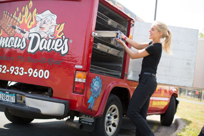 Famous Dave's BBQ Team Member taking food out of a Famous Dave's Catering Van