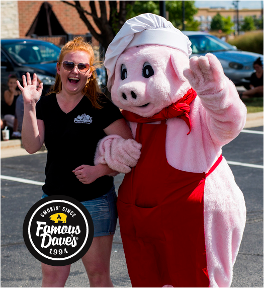 Famous Dave's BBQ pig mascot with team member smiling and waving