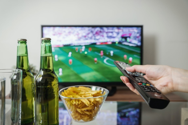 A superbowl fan is watching the game with snacks and BBQ ready for the fun!