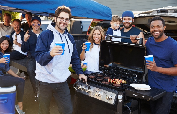 A group of friends get together to celebrate the game day with a bbq tailgate.