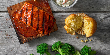 barbecue salmon on a wood slab, corn bread muffin and broccoli